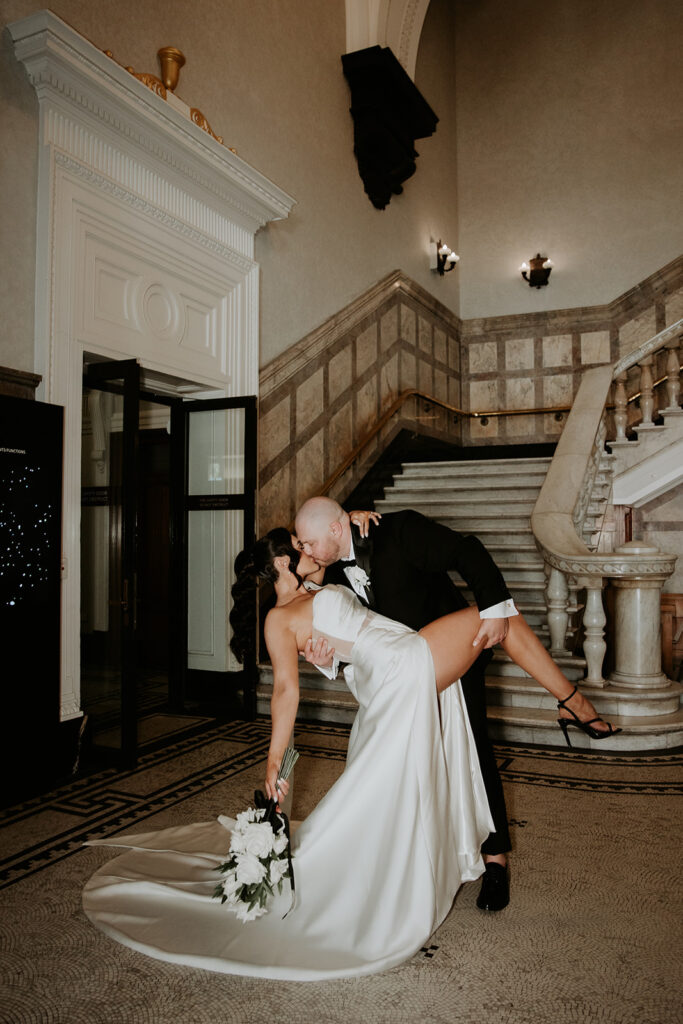 Wedding photos Brisbane City Hall bride and groom sharing a back bender kiss with the magnificent city hall steps in the background